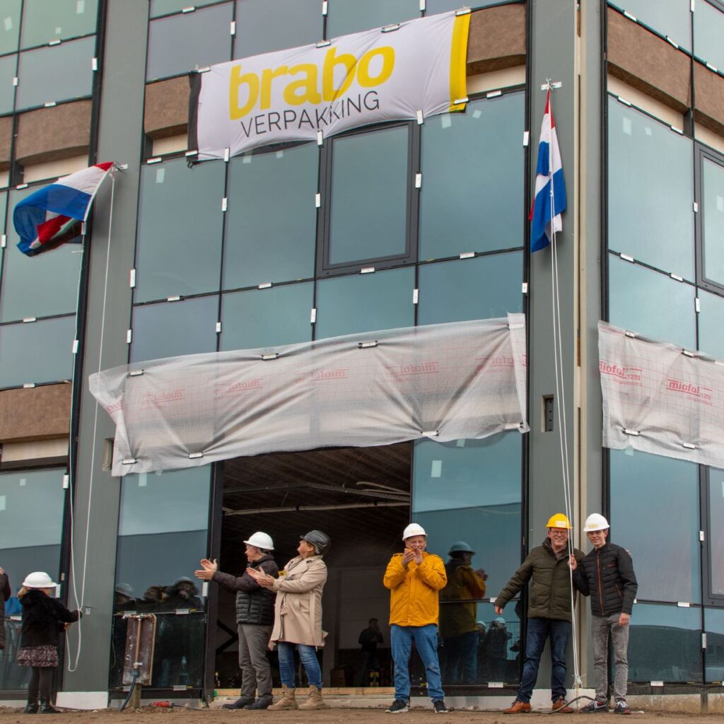 De vlag wordt gehesen bij de viering van het hoogste punt van de nieuwbouw van Brabo Verpakking in Gilze